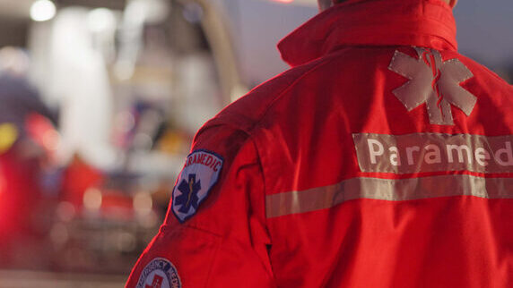 Back, man and paramedic walking to ambulance for emergency, ems service and healthcare in city. Rear view, medical professional and doctor outdoor at night for first aid, rescue operation and work